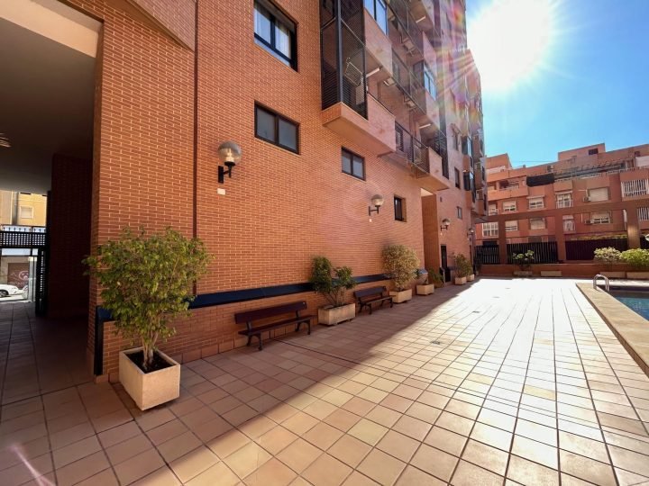 Zona común con bancos y plantas junto a la piscina