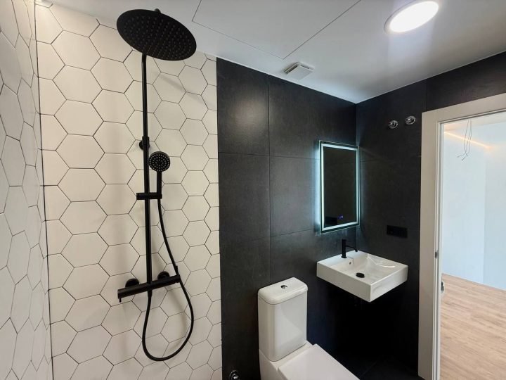 Baño con alicatado hexagonal blanco y paredes oscuras