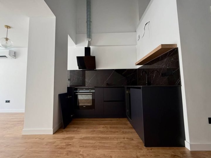 Cocina en L en negro con encimera de efecto mármol