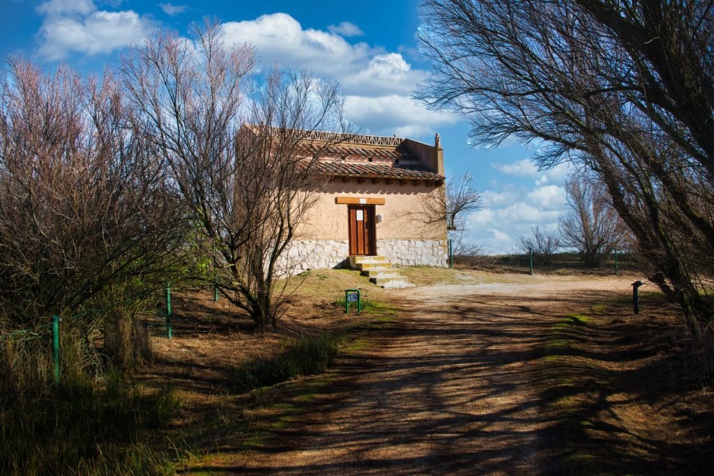 Casa de campo de piedra con tejado de teja junto a un camino de tierra